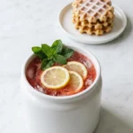 Erdbeer Limonade serviert mit Waffeln — spritziges Sommergetränk stilvoll präsentiert auf weißem Marmor