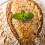 Dinkel-Sauerteigbrot frisch zubereitet — rundes, krustiges Sauerteigbrot mit rustikaler Mehlkruste im Dutch Oven Stil