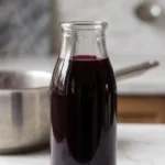 Holundersaft ohne Zuckerzusatz selber machen frisch zubereitet — tiefvioletter Saft in Glasflasche