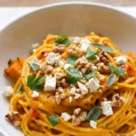 Perfekte Pasta mit cremiger Kürbissauce aus dem Ofen frisch zubereitet — leuchtend orangefarbene Pasta